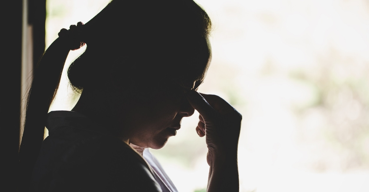 silhouette of a thoughtful sad woman with hand near her forehead